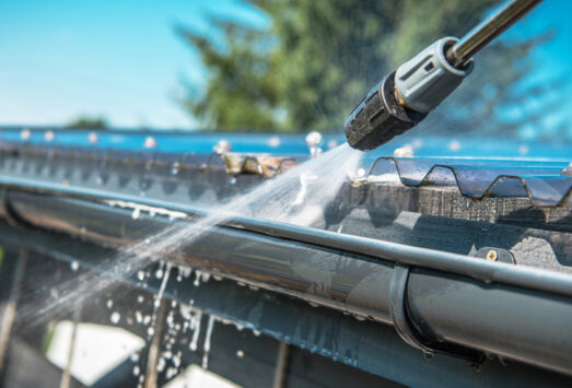 Rain Gutters Pressure Cleaning Spring Rain Gutters Cleaning Using Pressure Washer. Closeup Photo.
